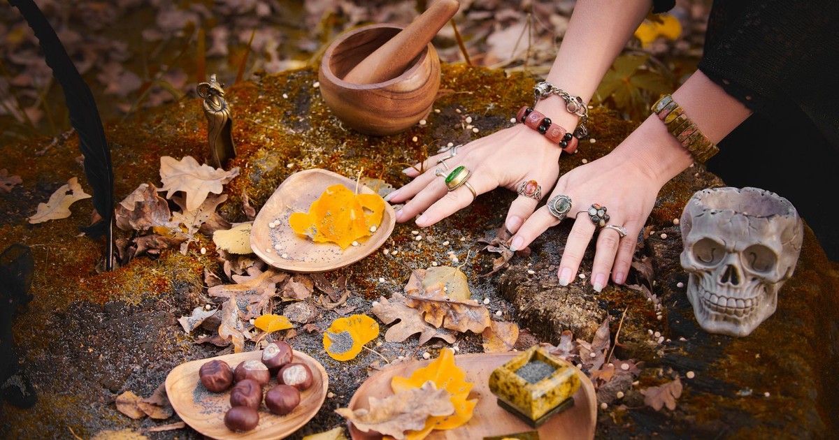 Atmospheric autumn ritual setup with hands, a skull, and natural elements on a mossy surface.
