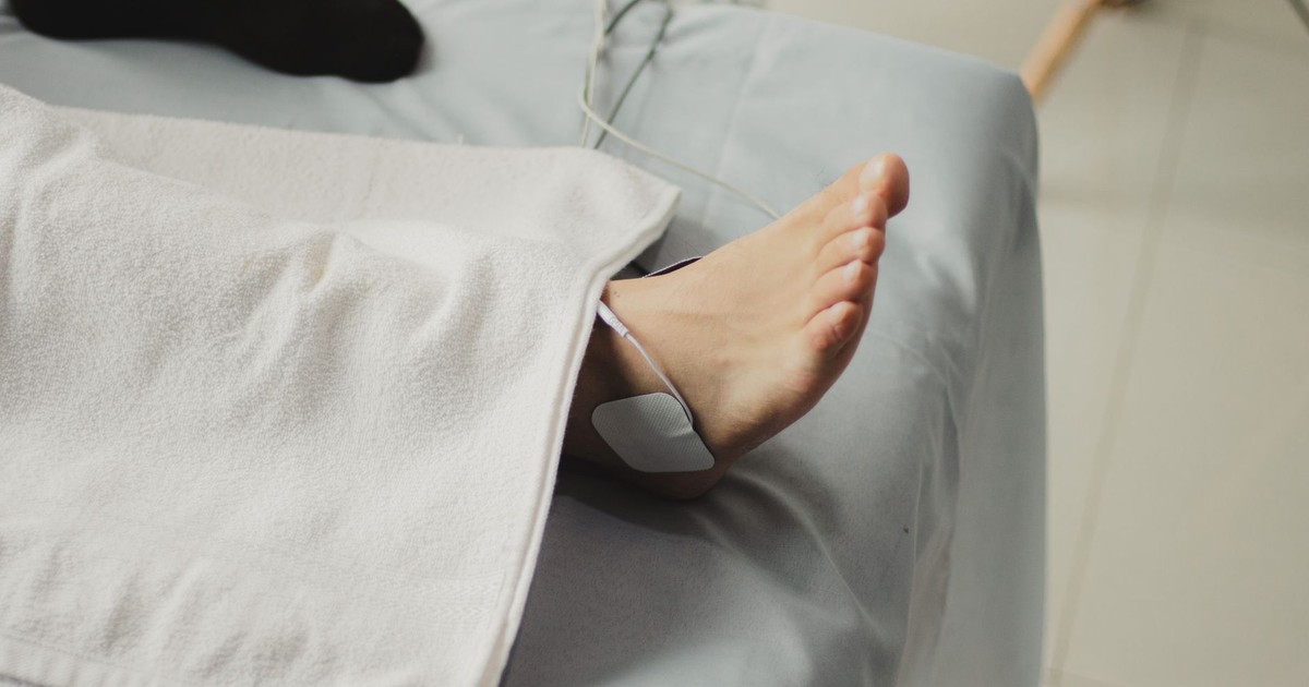 A close-up image of a bare foot with a medical electrode, suggesting a healthcare setting.